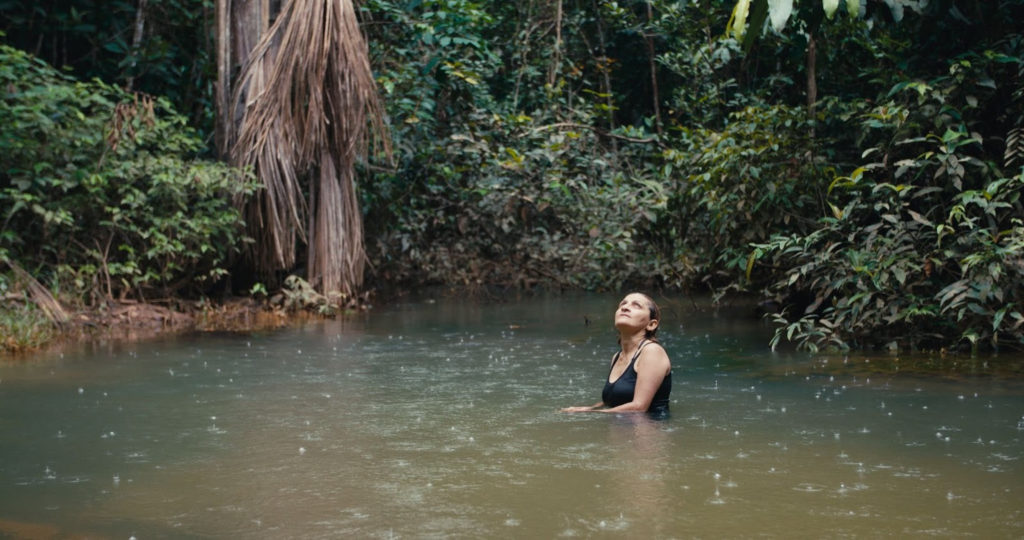 Neidinha Bandeira, ativista ambiental, toma banho em um rio na floresta amazônica (Crédito: Alex Pritz/Amazon Land Documentary)